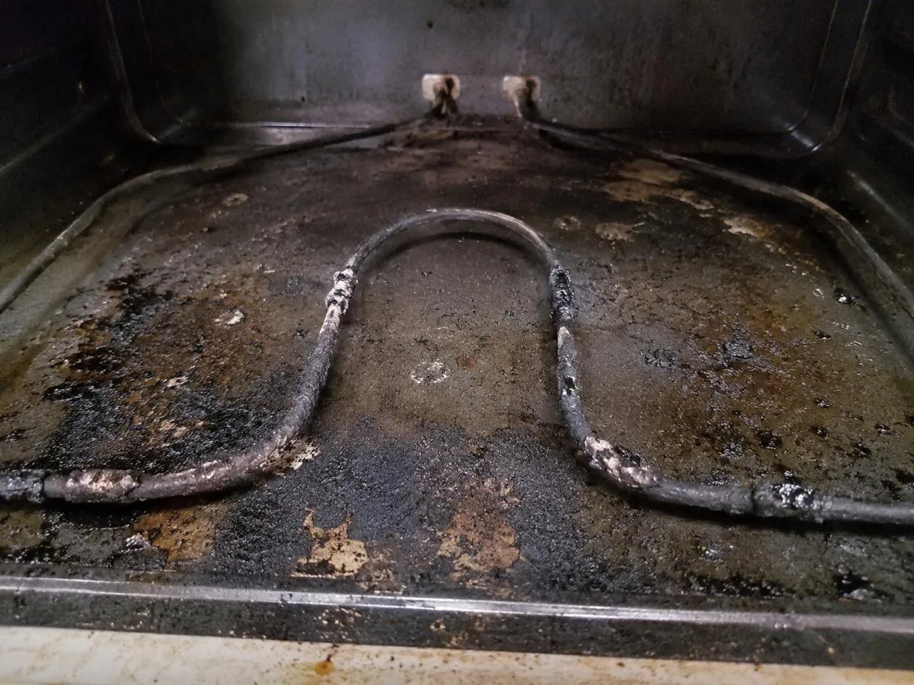 Burnt, greasy oven interior and bake element before repair