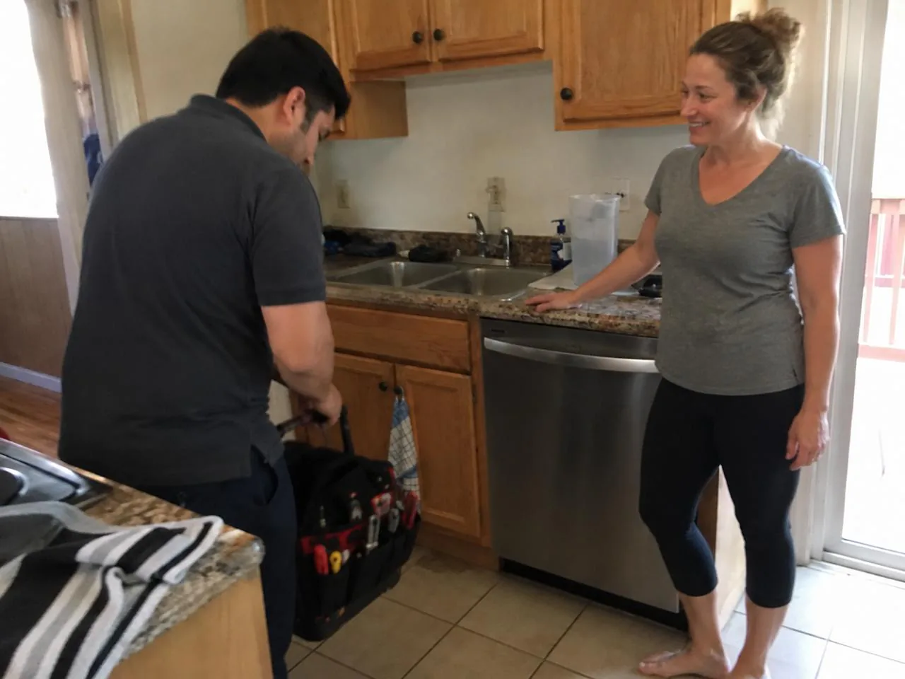Technician and homeowner beside a repaired kitchen appliance